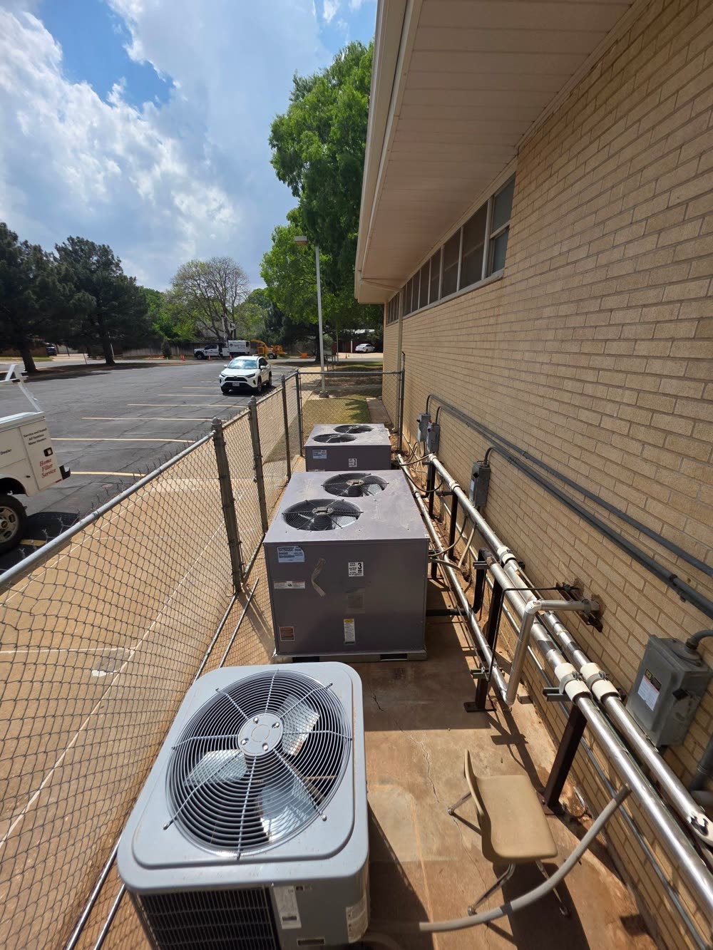 A row of condenser units along the brick wall of a building, a Duncan job